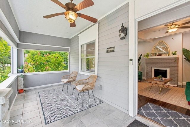 sunroom / solarium with ceiling fan and a brick fireplace