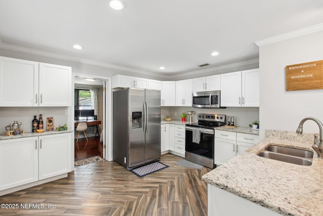 kitchen with appliances with stainless steel finishes, sink, white cabinets, and light stone counters