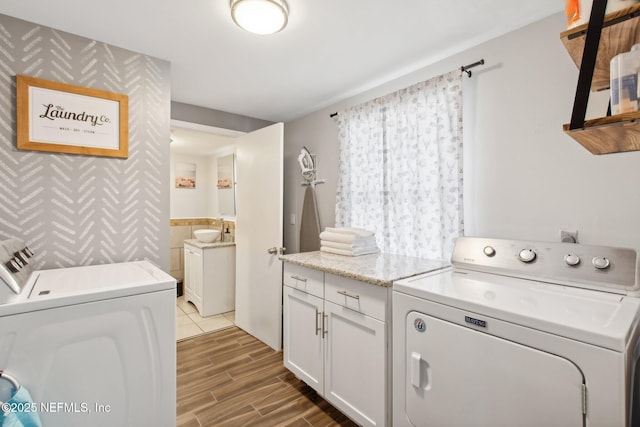 washroom with cabinets, washing machine and clothes dryer, and sink