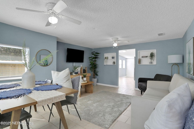 tiled living room featuring ceiling fan and a textured ceiling