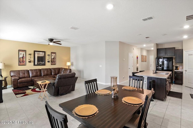 tiled dining space featuring sink, a textured ceiling, and ceiling fan