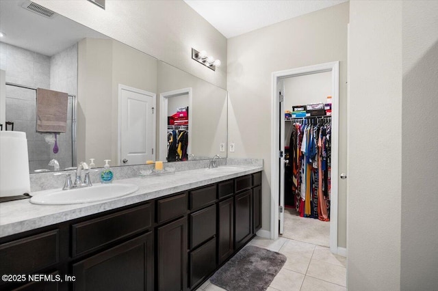 bathroom featuring tile patterned flooring, vanity, and a tile shower