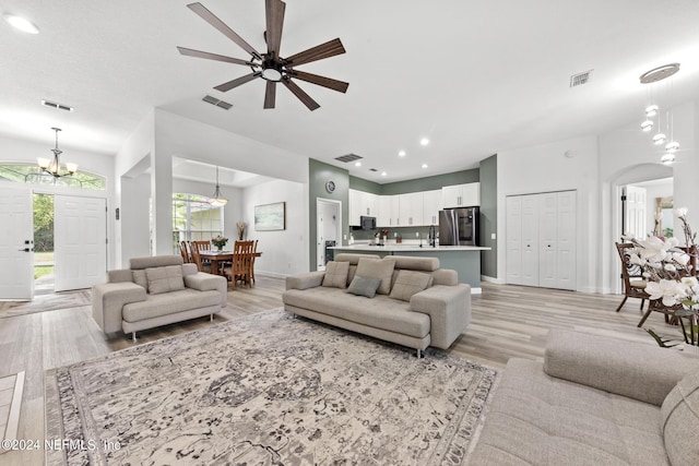 living room featuring ceiling fan with notable chandelier, sink, and light hardwood / wood-style flooring