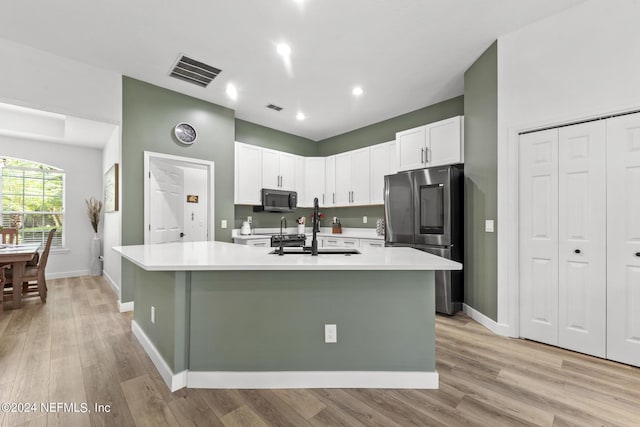 kitchen with appliances with stainless steel finishes, sink, a kitchen island with sink, and white cabinets