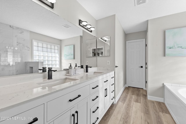 bathroom featuring vanity, shower with separate bathtub, wood-type flooring, and a textured ceiling