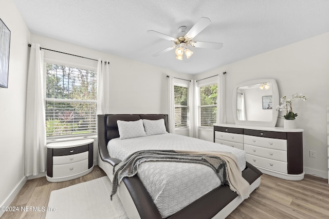 bedroom with ceiling fan, a textured ceiling, and light wood-type flooring