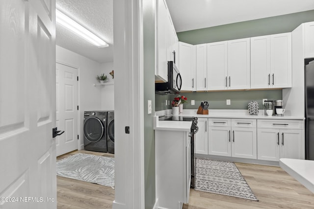 laundry room featuring washing machine and clothes dryer, light hardwood / wood-style floors, and a textured ceiling