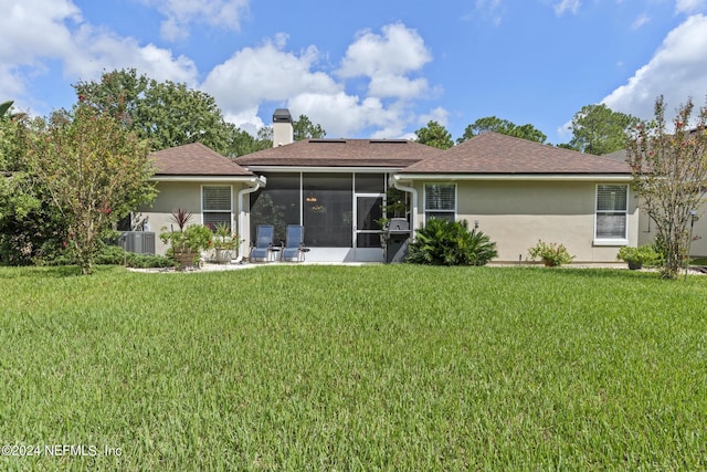 rear view of house with solar panels, a sunroom, a yard, and central air condition unit