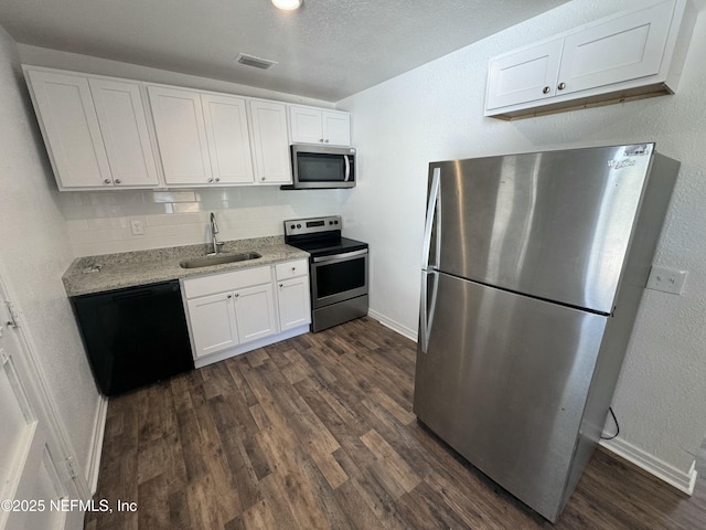 kitchen with dark wood-type flooring, sink, white cabinetry, stainless steel appliances, and backsplash