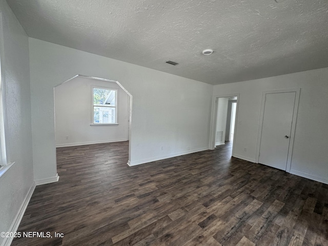 additional living space with dark wood-type flooring and a textured ceiling