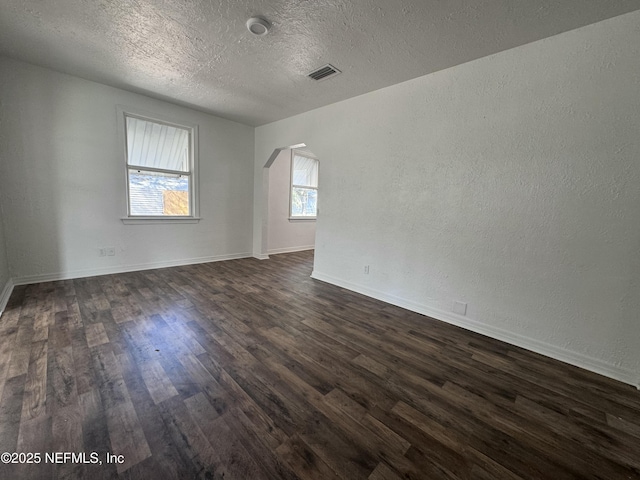 spare room featuring dark hardwood / wood-style flooring and a textured ceiling