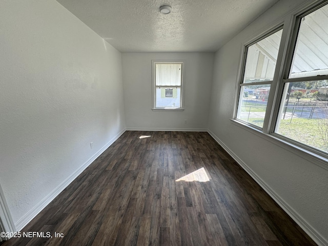 unfurnished room featuring a healthy amount of sunlight, a textured ceiling, and dark hardwood / wood-style flooring