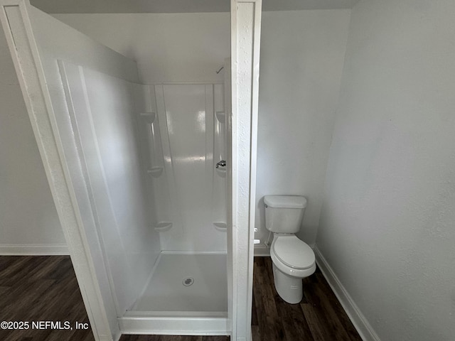 bathroom with hardwood / wood-style flooring, toilet, and a shower