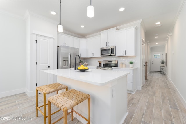 kitchen with white cabinetry, appliances with stainless steel finishes, a center island with sink, and a kitchen breakfast bar