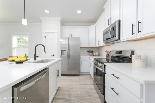 kitchen featuring stainless steel appliances, sink, white cabinets, and decorative light fixtures