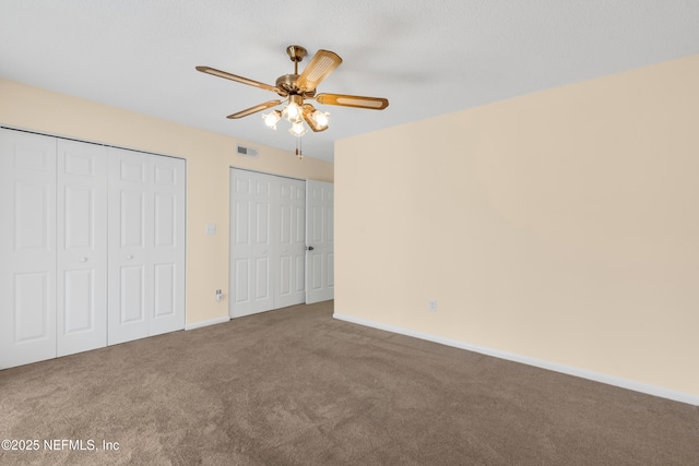 unfurnished bedroom with multiple closets, ceiling fan, and carpet floors