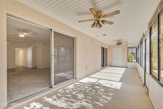 unfurnished sunroom featuring ceiling fan