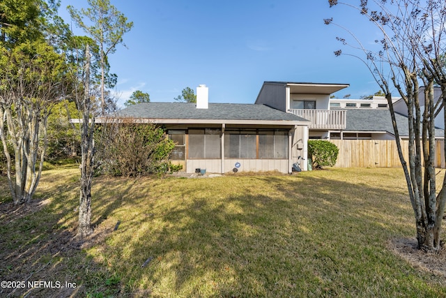 back of house featuring a lawn, a sunroom, and a balcony