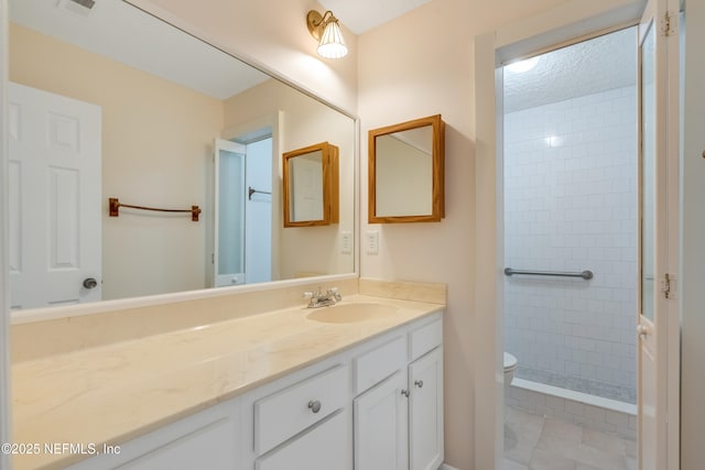 bathroom with tiled shower, vanity, and toilet