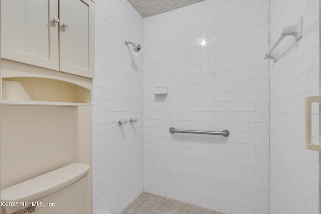 bathroom featuring tiled shower and toilet