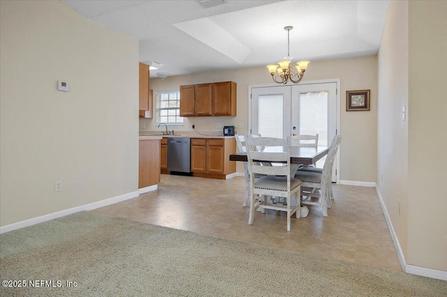 dining area featuring a chandelier, a raised ceiling, sink, and french doors