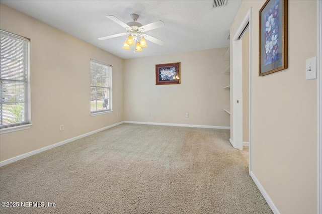 spare room featuring light carpet, a textured ceiling, and ceiling fan