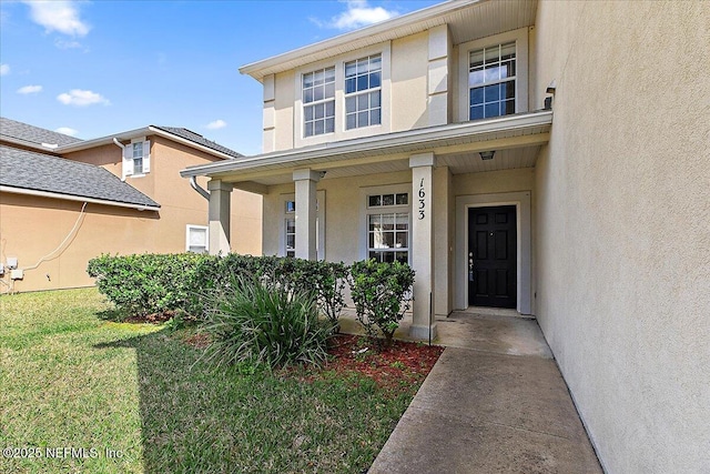 property entrance with a lawn and stucco siding