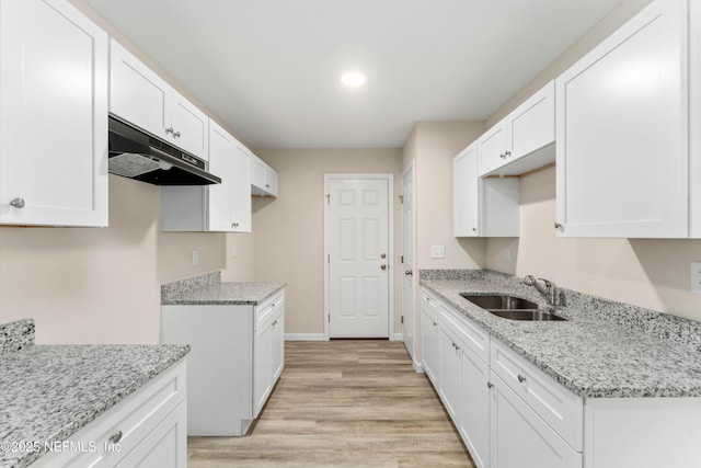 kitchen featuring white cabinetry, light stone countertops, sink, and light hardwood / wood-style flooring