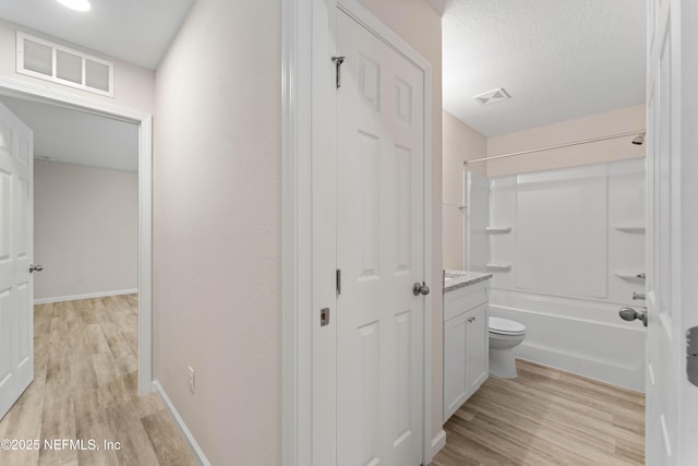 full bathroom with hardwood / wood-style floors, vanity,  shower combination, toilet, and a textured ceiling