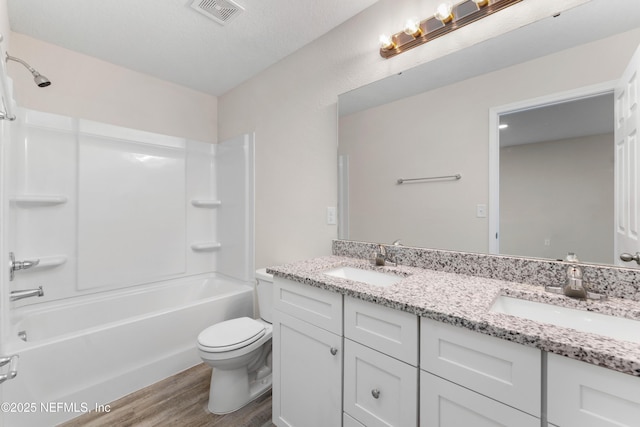 full bathroom featuring hardwood / wood-style flooring, shower / washtub combination, toilet, and vanity