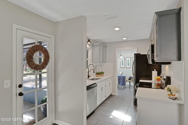 kitchen featuring sink, light tile patterned floors, appliances with stainless steel finishes, gray cabinetry, and decorative backsplash