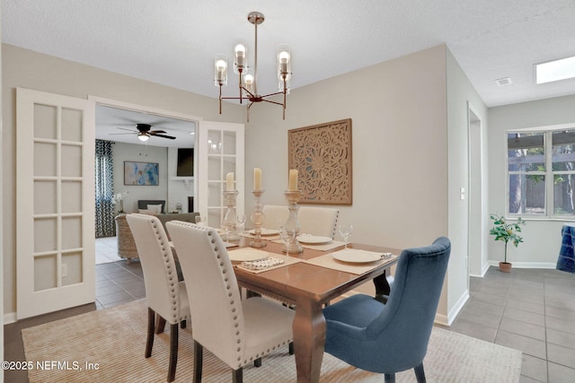 dining area with tile patterned flooring, a textured ceiling, and a notable chandelier