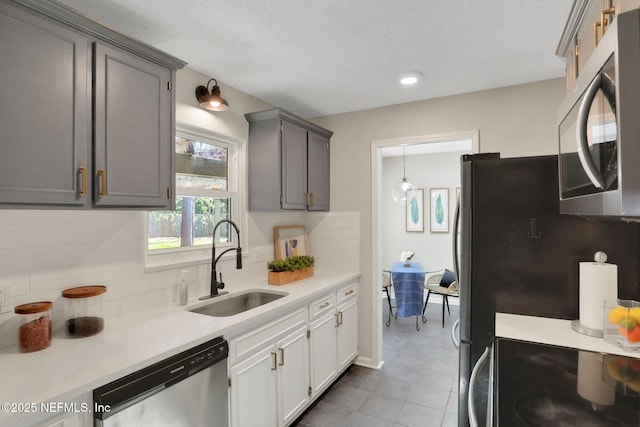 kitchen featuring tasteful backsplash, sink, gray cabinets, and appliances with stainless steel finishes