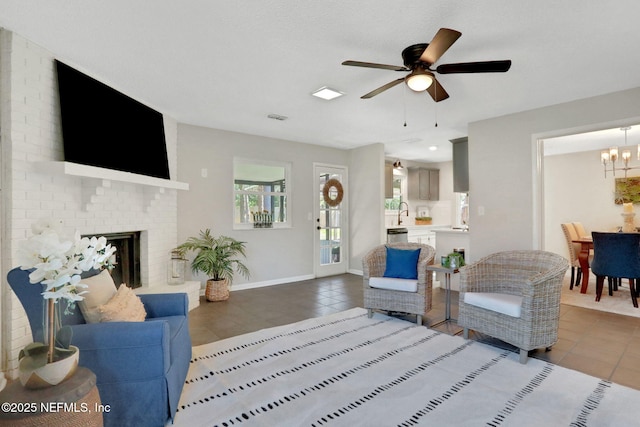 living room featuring ceiling fan with notable chandelier, a fireplace, and tile patterned flooring