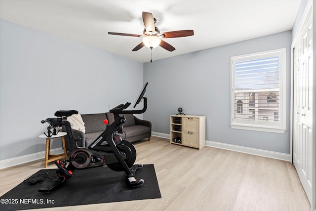 exercise room with light wood-style flooring, baseboards, and ceiling fan