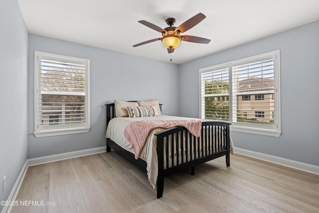 bedroom with light wood finished floors, baseboards, and a ceiling fan