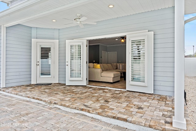 view of exterior entry featuring a ceiling fan and a patio area