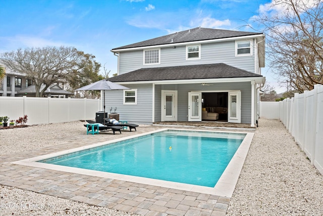 back of property with a fenced in pool, a patio area, a fenced backyard, and roof with shingles