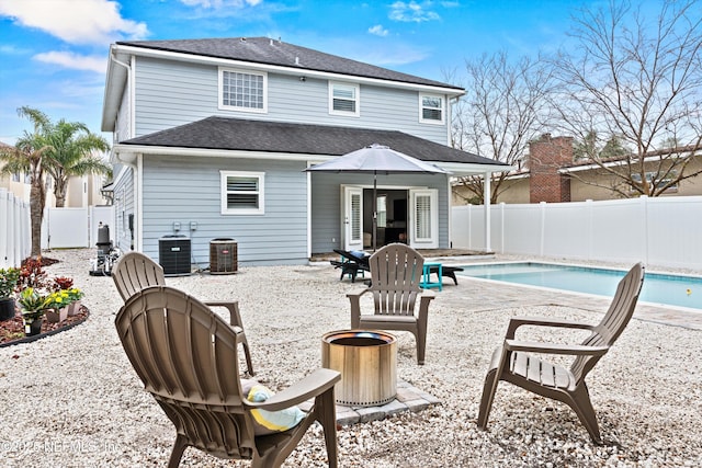 rear view of house with central AC, an outdoor fire pit, a fenced backyard, and a fenced in pool