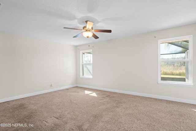 carpeted empty room with a textured ceiling, ceiling fan, and baseboards