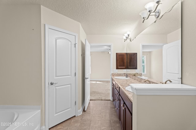 bathroom with a washtub, a sink, a textured ceiling, and double vanity