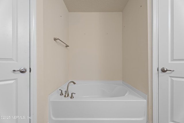 full bath featuring a garden tub and a textured ceiling