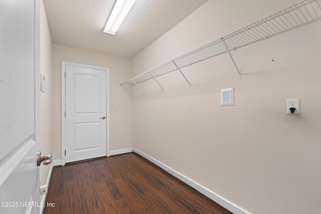 clothes washing area with a textured ceiling, dark wood-style floors, and baseboards