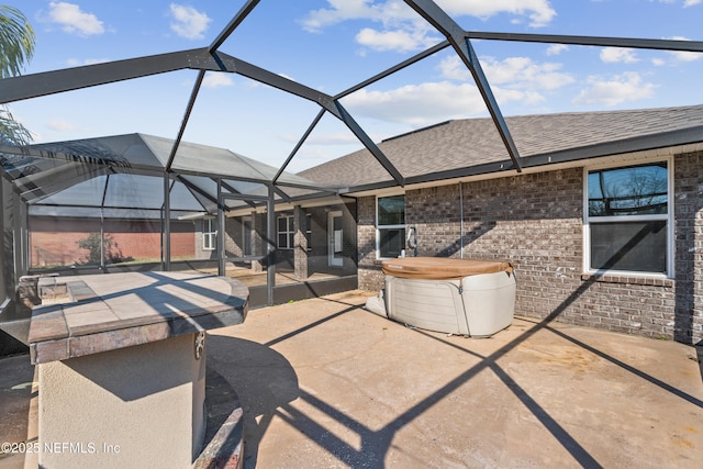 view of patio / terrace with glass enclosure and a hot tub