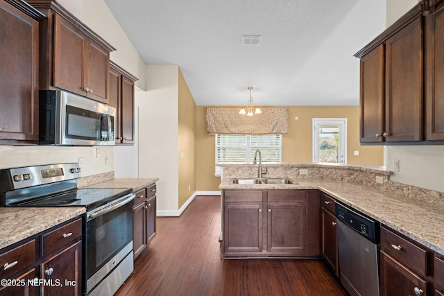 kitchen with stainless steel appliances, visible vents, hanging light fixtures, a sink, and dark brown cabinets