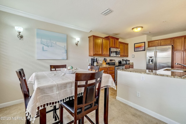 carpeted dining space featuring crown molding and sink