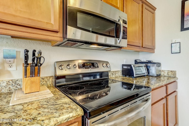 kitchen with appliances with stainless steel finishes and light stone counters