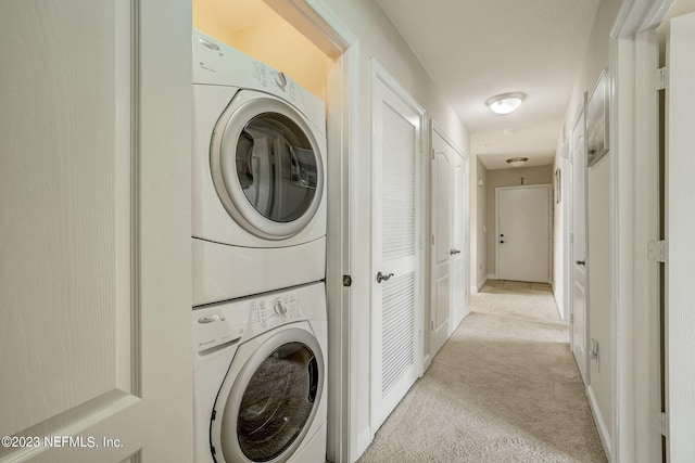 clothes washing area with stacked washer and clothes dryer and light carpet