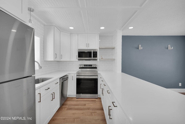 kitchen with sink, tasteful backsplash, light wood-type flooring, stainless steel appliances, and white cabinets