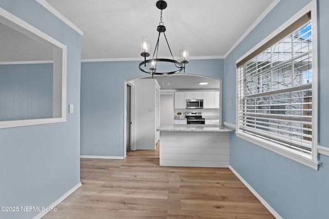 kitchen featuring crown molding, a chandelier, light wood-type flooring, stainless steel appliances, and white cabinets